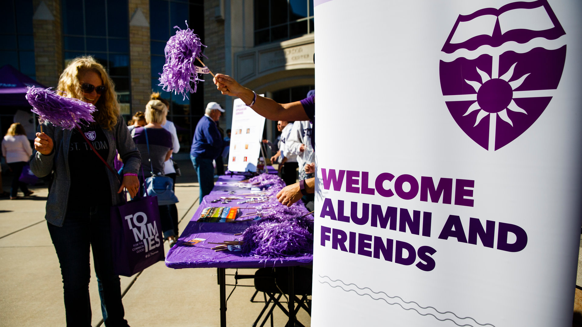 people stand by a welcome sign during an alumni event