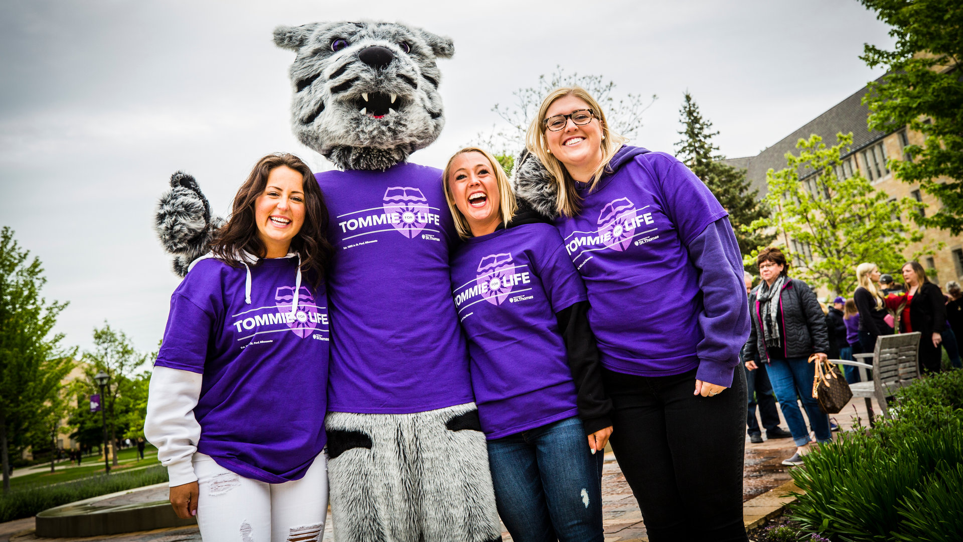 three women pose with Tommie the mascot during reunion weekend