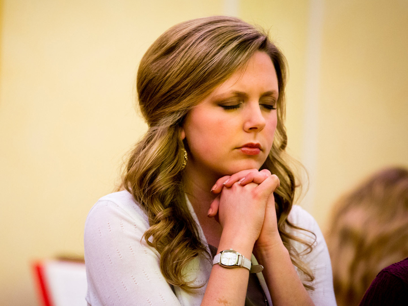 a woman praying at a faith event
