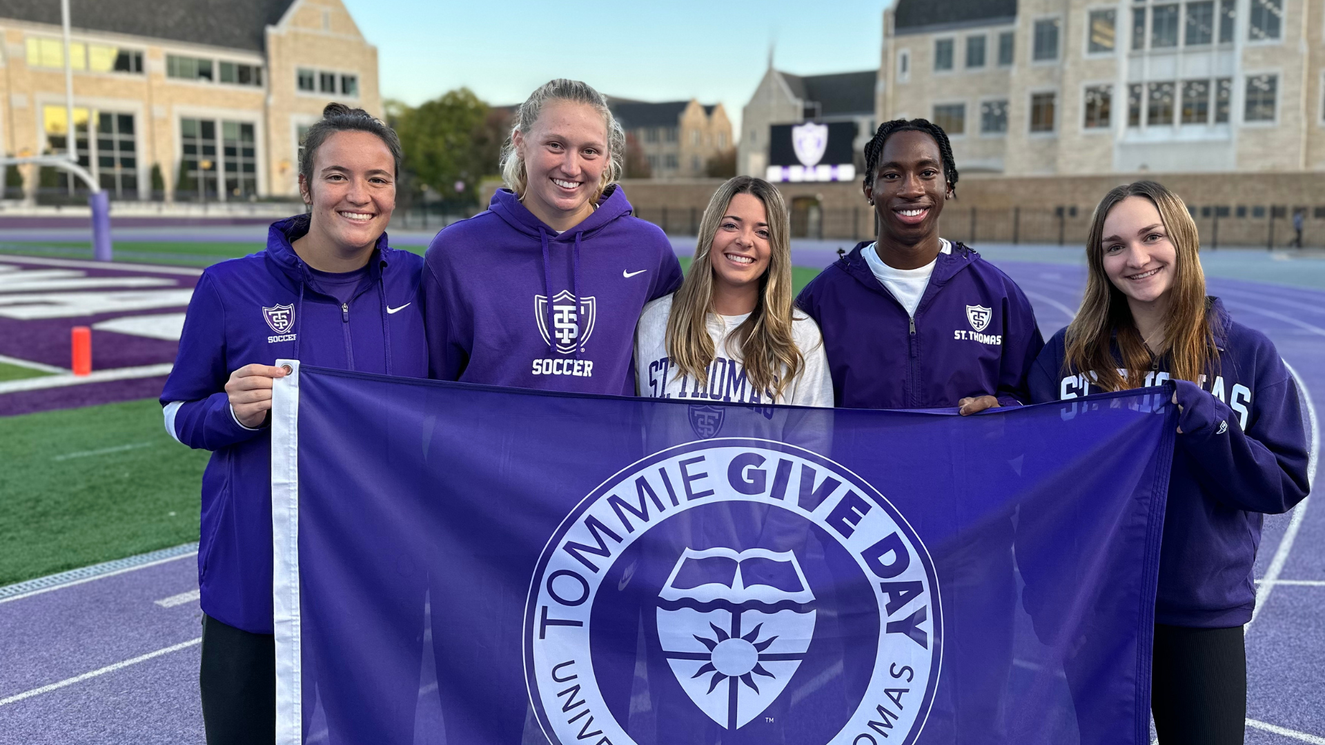Students standing together holding Tommie Give Day flag