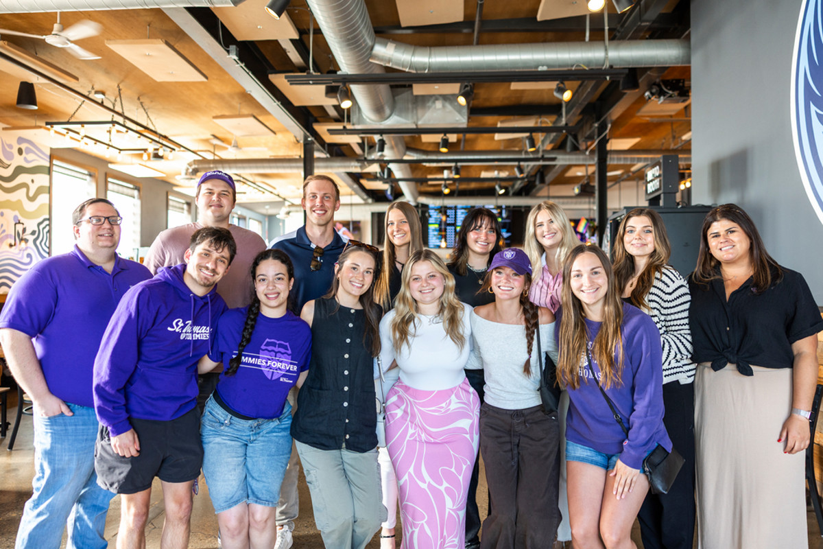 Four Tommie alumni smile for a photo together at Tommie Hops and Hype.