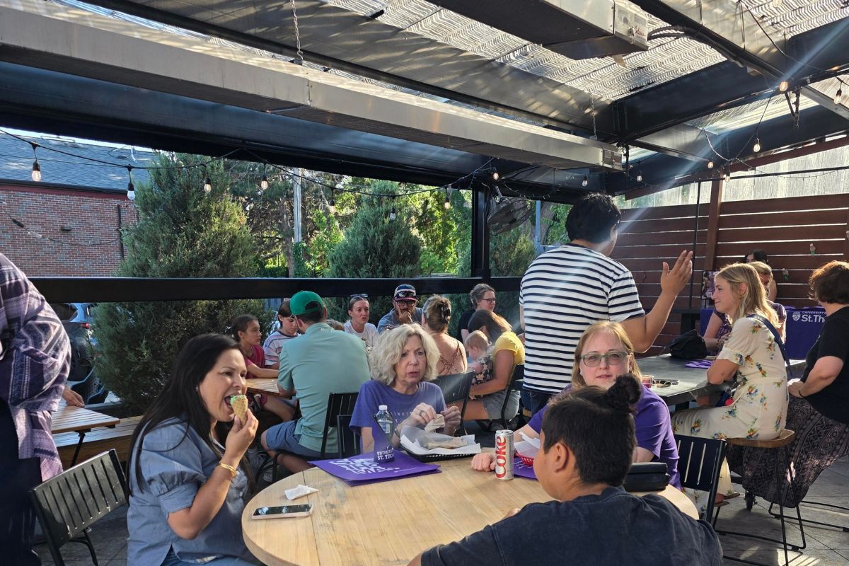 groups of people gather at tables on a sunny patio