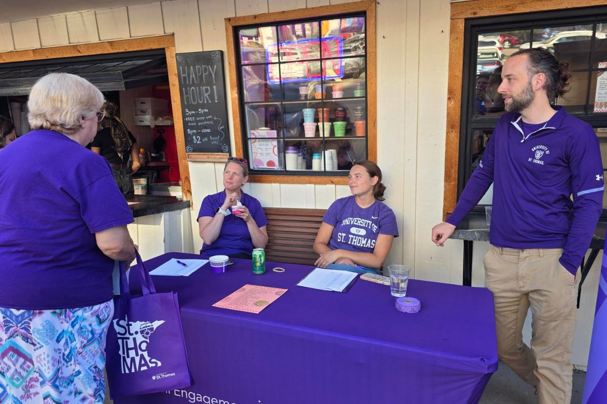 volunteers clad in purple St. Thomas shirts greet pop-in attendees