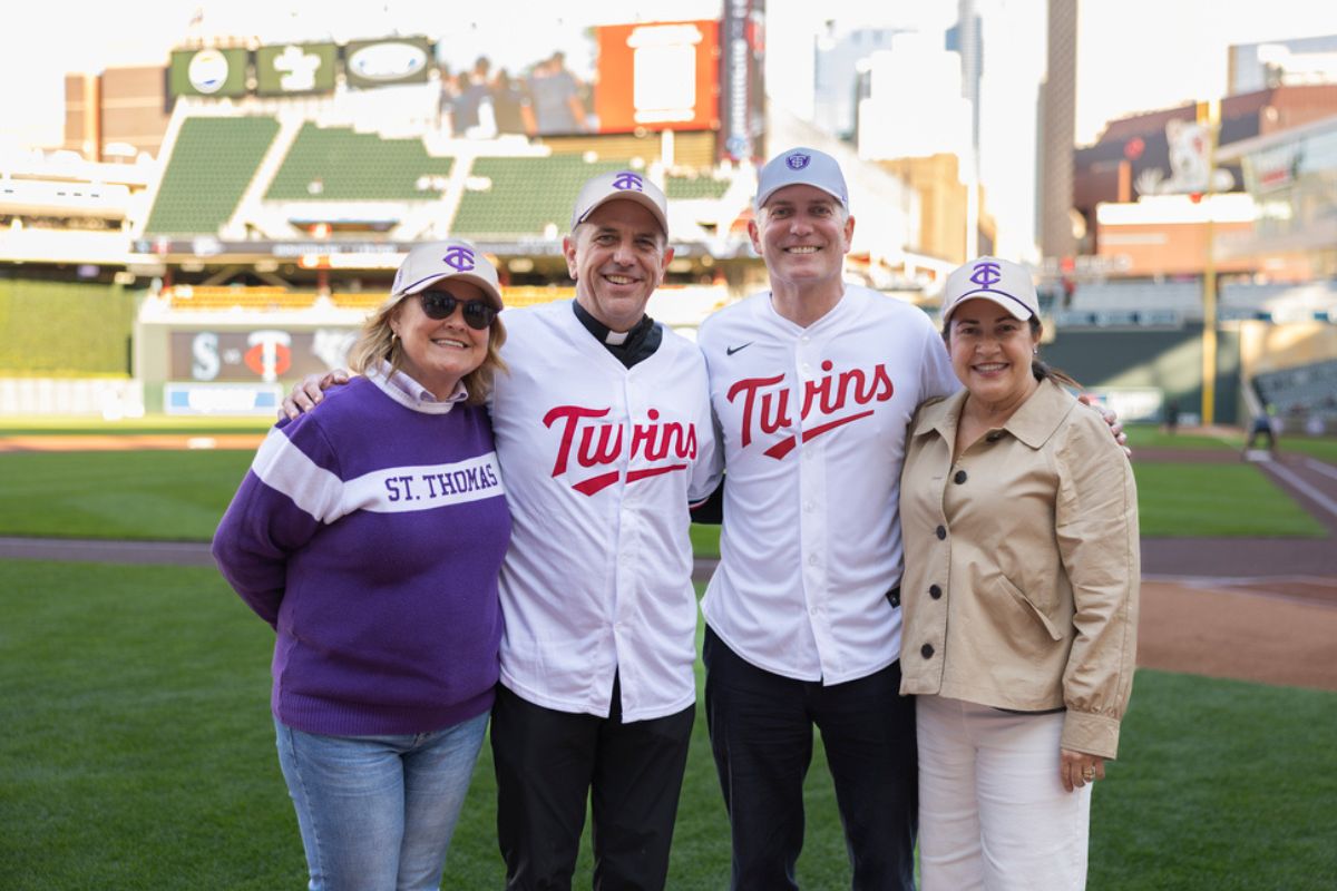 Father Collins and President Vischer pose for a group photo with their wives on the field at Target Field