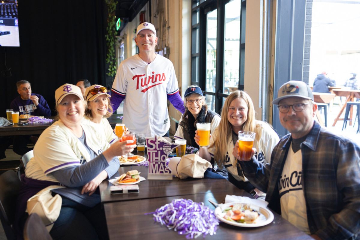 President Vischer poses with a group of Tommies seated at a table