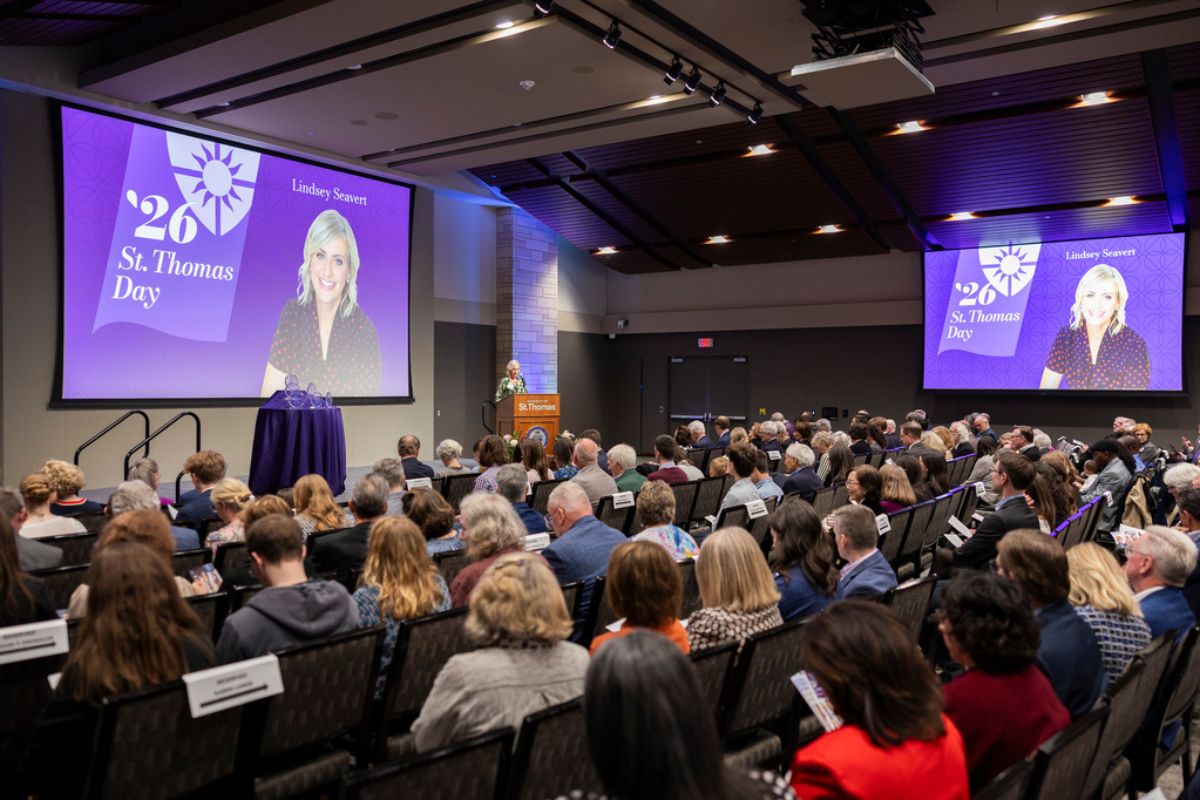 The audience looks on at a purple powerpoint slide