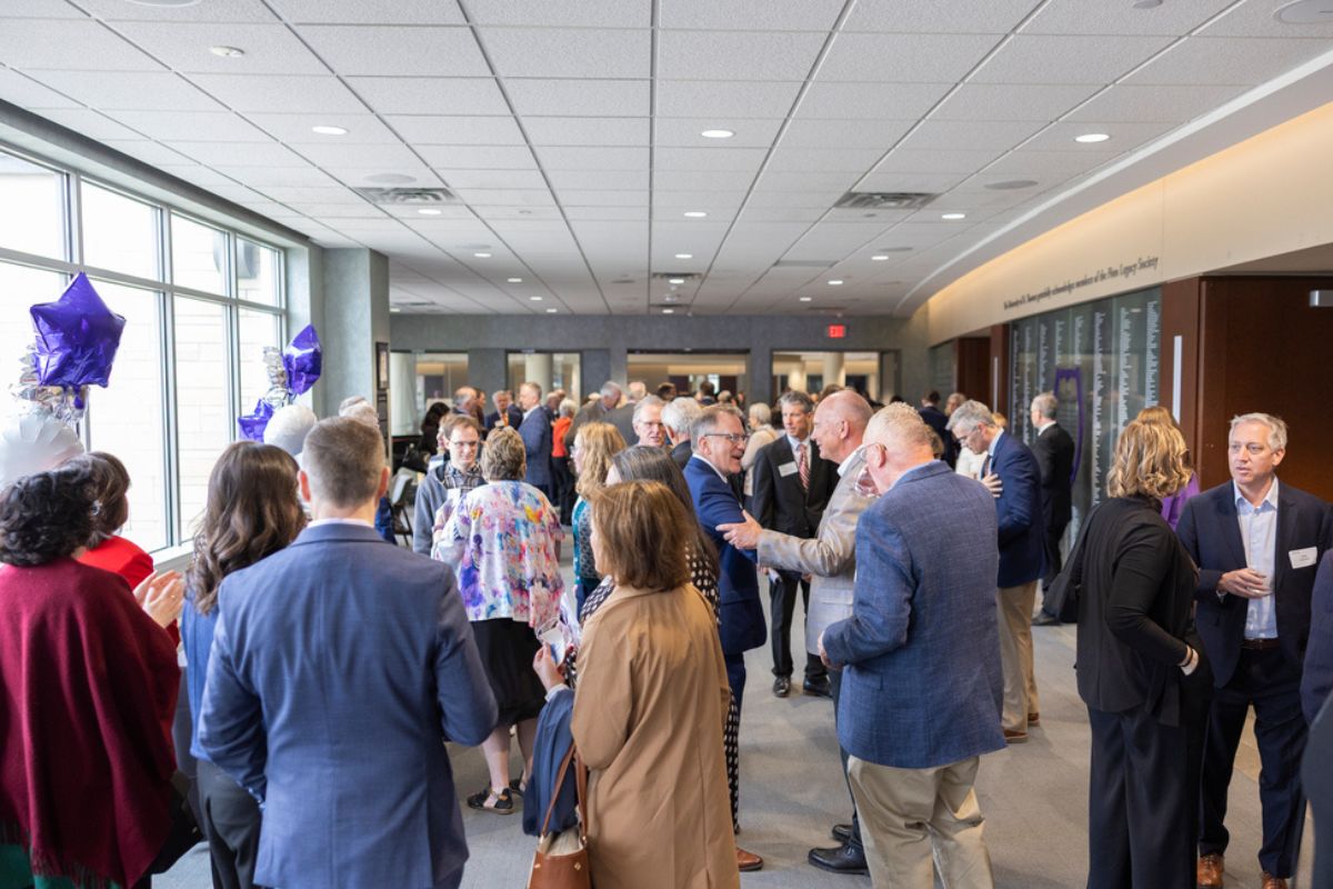 Attendees socialize in the hallway outside Woulfe Alumni Hall