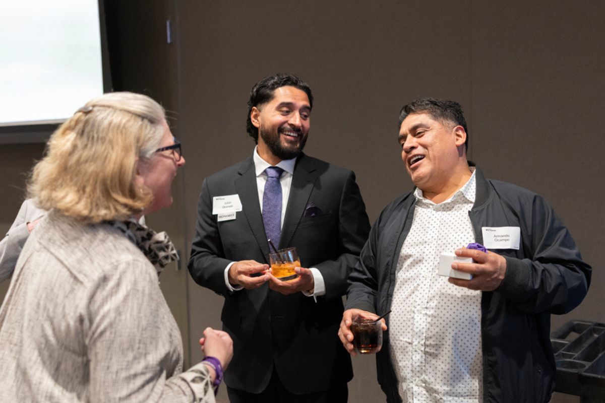 Julián Ocampo smiles and laughs with two attendees