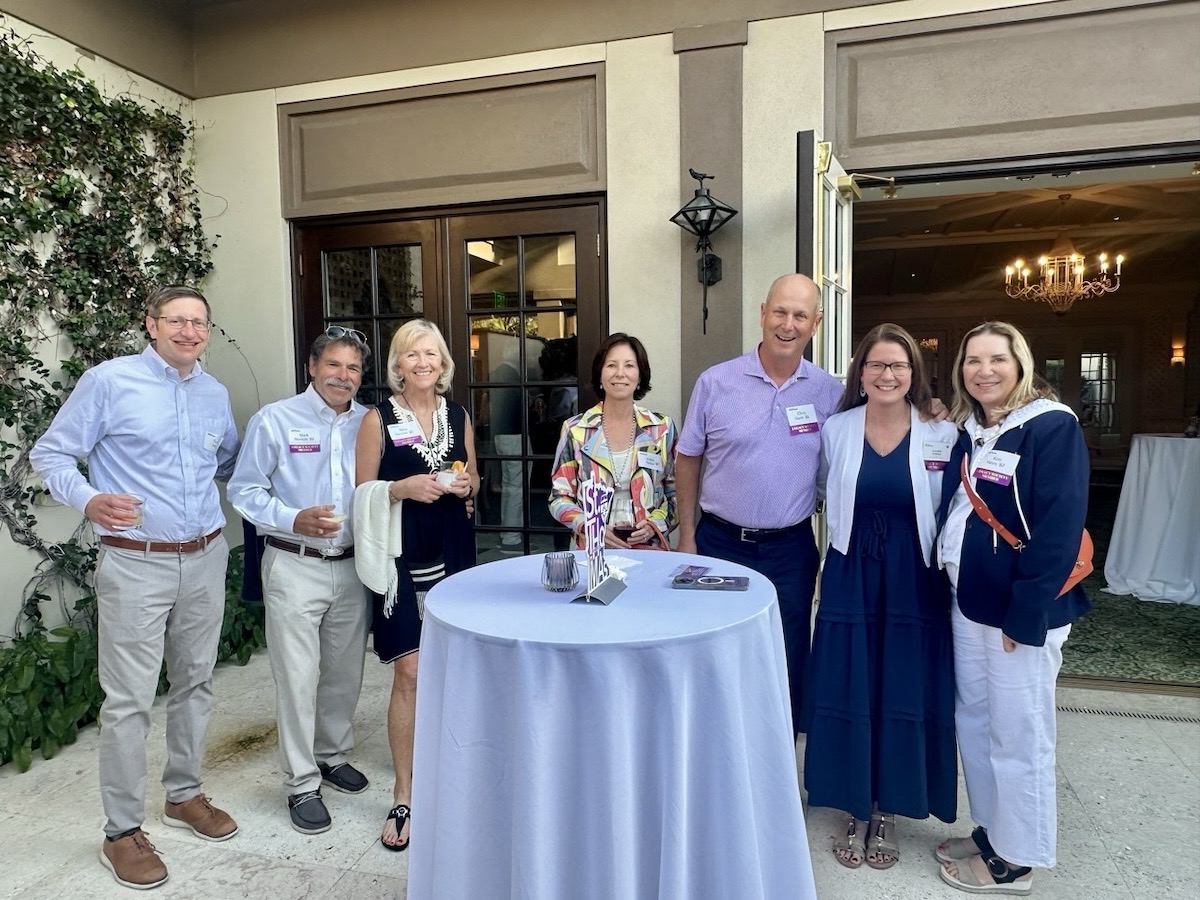 A group of eight Tommies pose together and smile for a photo taken on the patio at the Royal Poinciana Golf Club