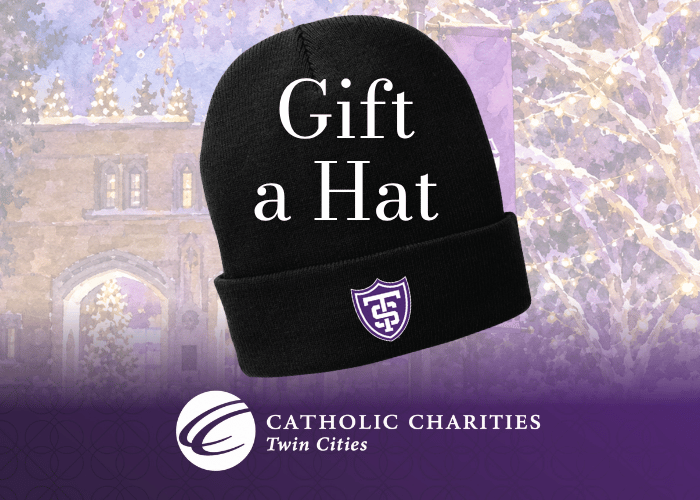 A black hat with a St. Thomas logo on top of a beautiful winter scene