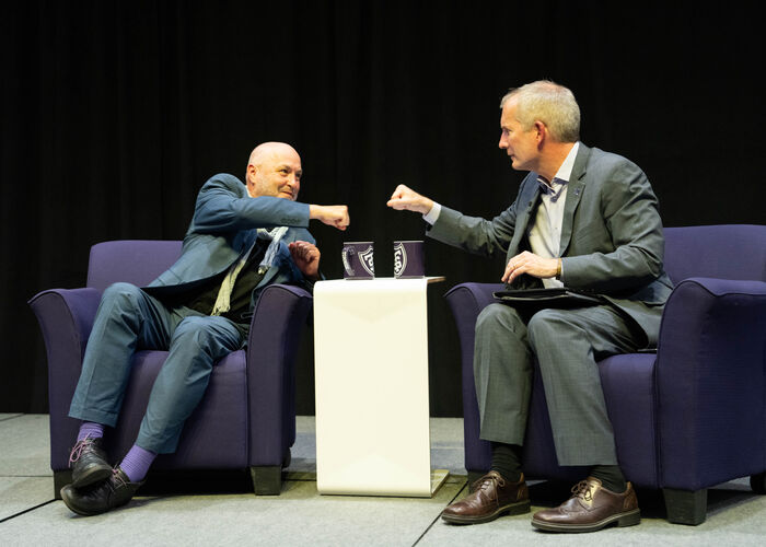 Colum McCann and President Rob Vischer bump fists on stage to greet each other for the Finding Forward event