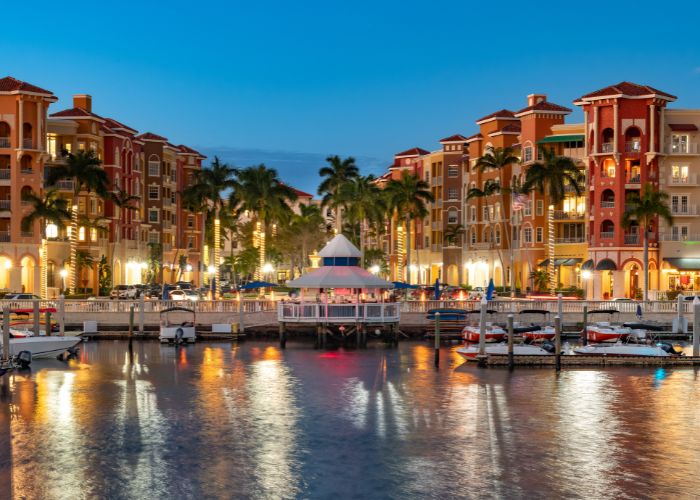 A Naples bay at sunset. Colorful buildings and lights are reflected on ocean water.
