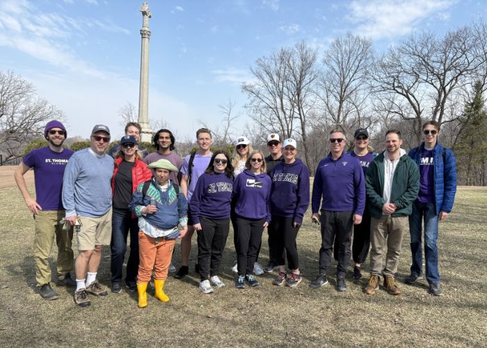 Tommies pose for a photo in front of The Monument in Shadow Falls Park after a Mississippi River cleanup for Tommie Volunteer Week.