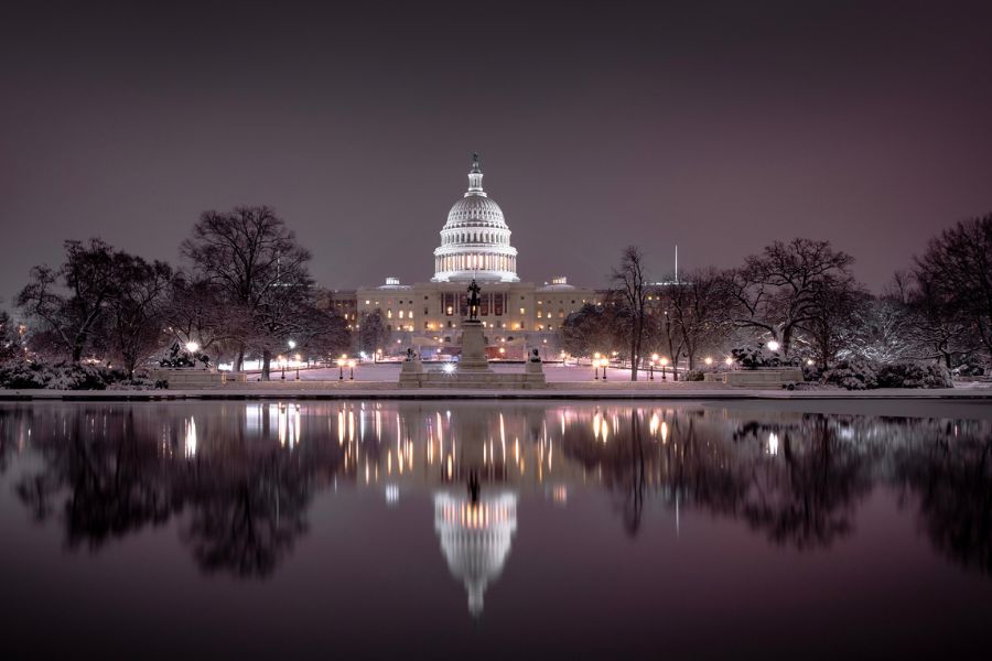 The Capitol building in Washington D.C. at night. The reflecting pool is in the foreground.