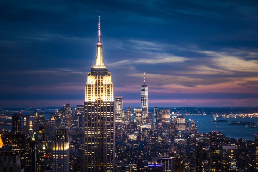 The NYC skyline lit up at night with the Chrysler building in the foreground