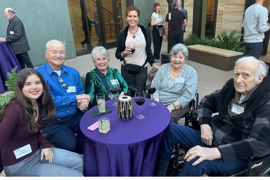 TOTR Phoenix attendees sit at purple tables in the courtyard at the Musical Instrument Museum and smile for a photo.