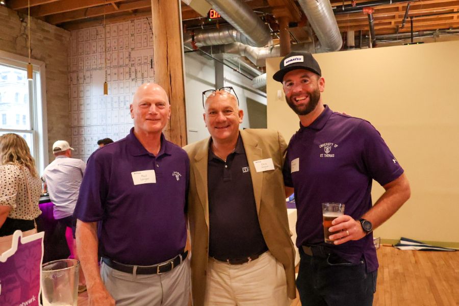 Three Tommies smile into the camera during the Tommies On the Road social in Milwaukee