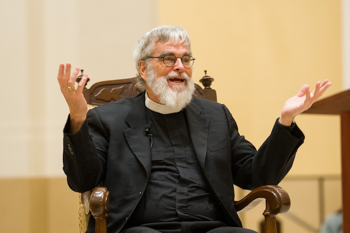 Brother Guy speaks animatedly from a chair in the Chapel of St. Thomas Aquinas