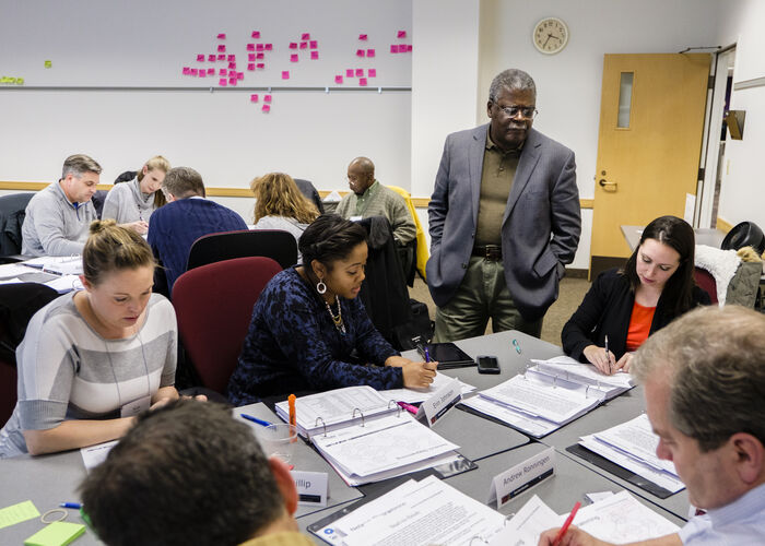 A professor watches over group work during an Executive Education class