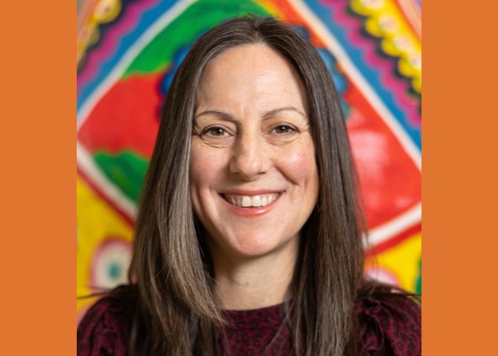 Dr. Kari Zimmerman smiles into the camera against a colorful orange graphic background