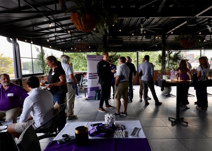 A crowd of people talks on the patio at The Elm