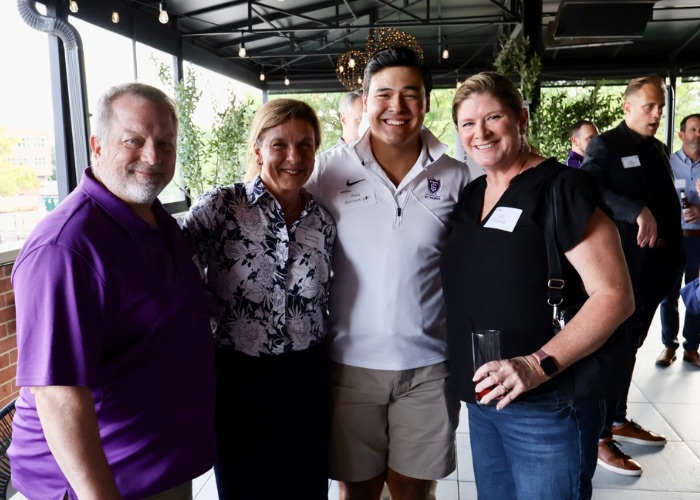 Four Tommies wearing purple smile for a group photo
