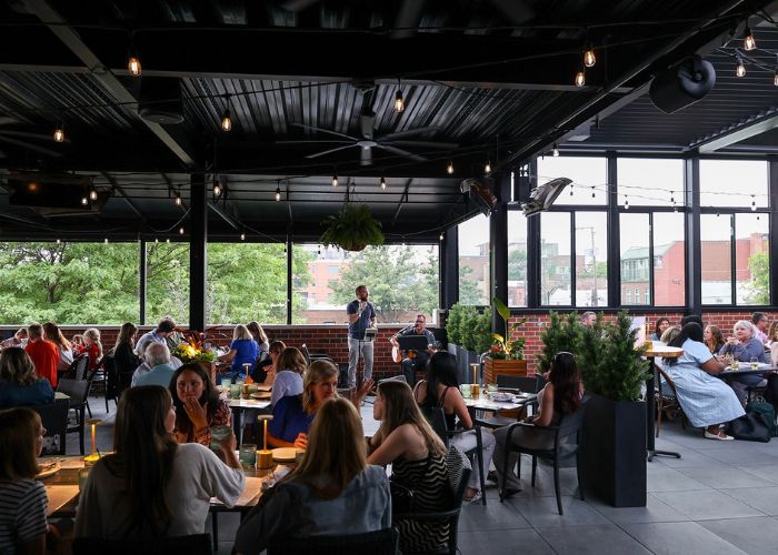 The interior patio of The Elm is lit up with string lights and people dining at tables