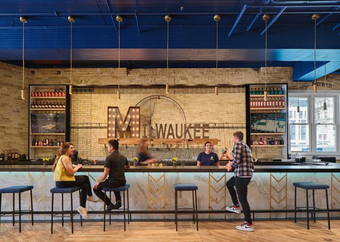 The interior bar of Central Standard Kitchen. "Milwuakee" is written on the wooden wall and string lights hang over the bar.