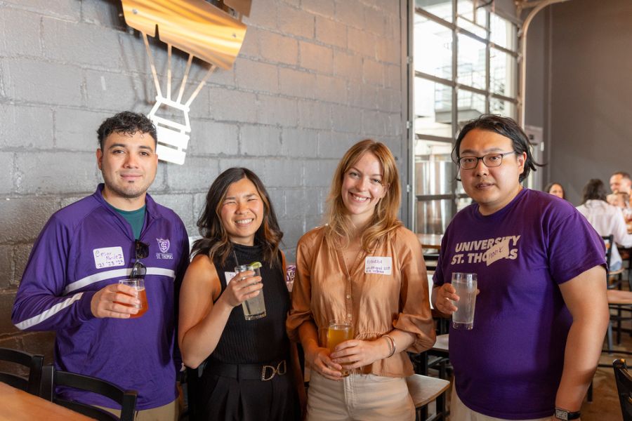 Four Tommie alumni smile for a photo together at Tommie Hops and Hype.