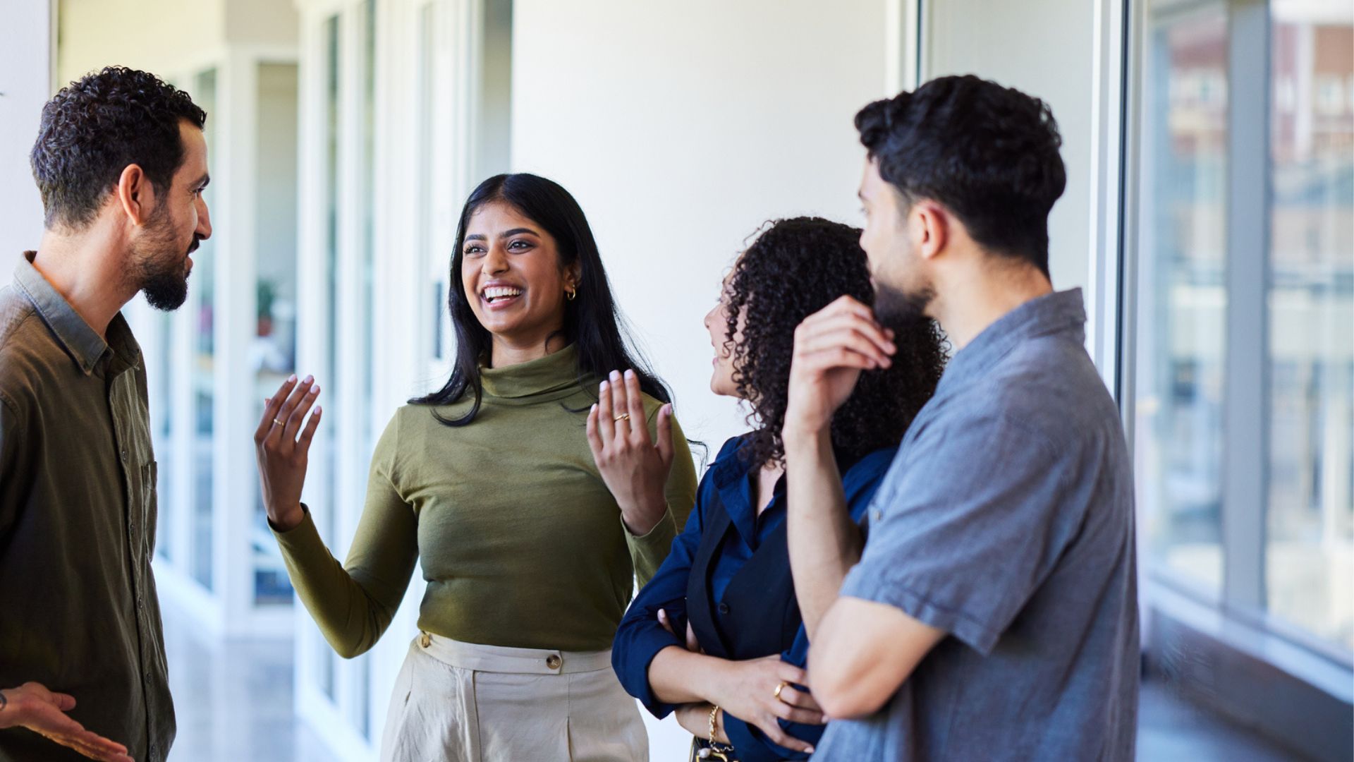 Four young adults talk animatedly in a corridor.