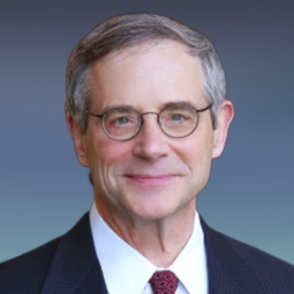 Dr. John P. Knoedler ’73 wears a suit and smiles into the camera against a blue background