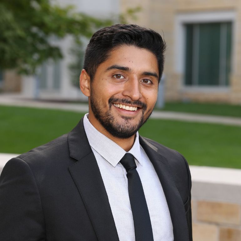 Julian Ocampo smiles into the camera for a portrait photo taken in front of Anderson Student Center