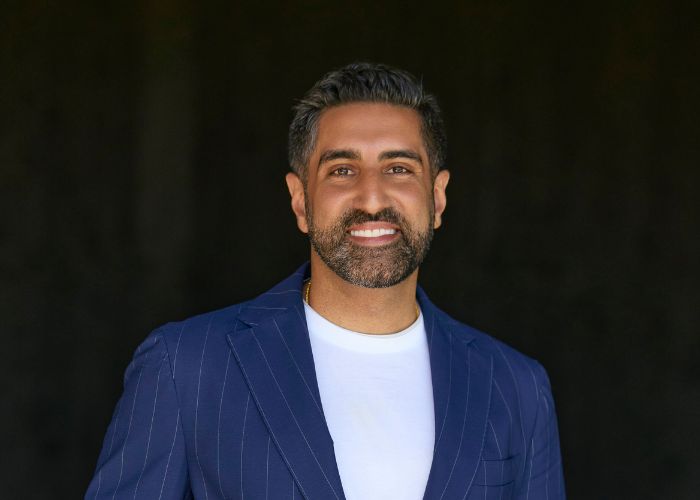 Vik Uppal wears a blue suit and smiles into the camera
