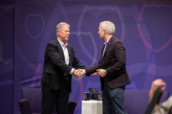 two men shaking hands on a stage