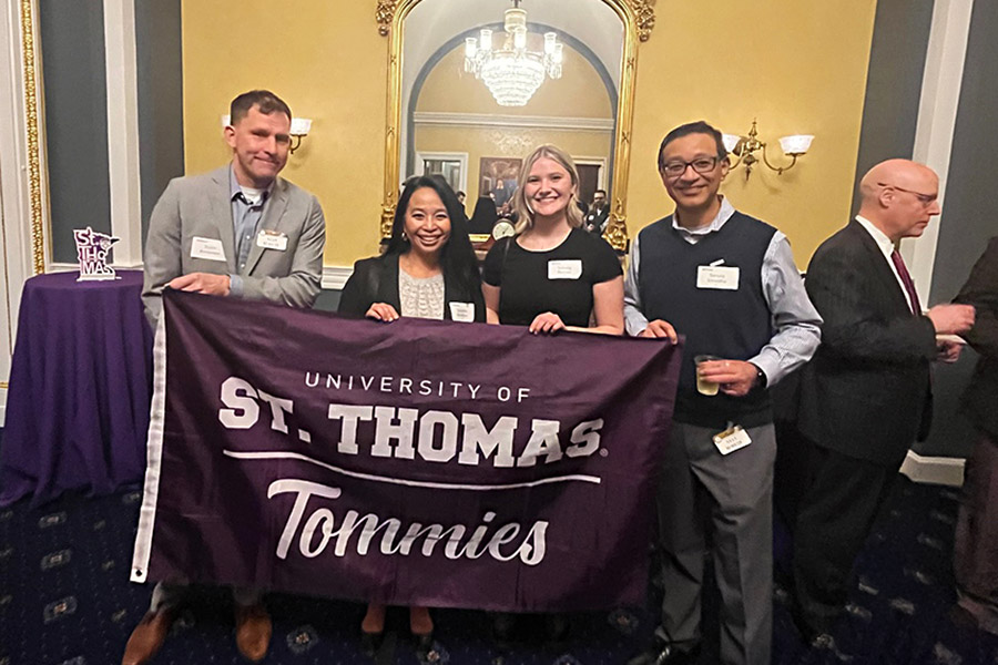 Alumni pose with St. Thomas flag during Tommies On the Road: Washington, D.C. 