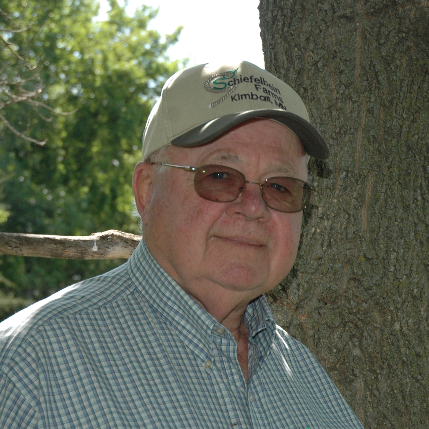 frank schiefelbein standing in front of tree with schiefelbein farms hat