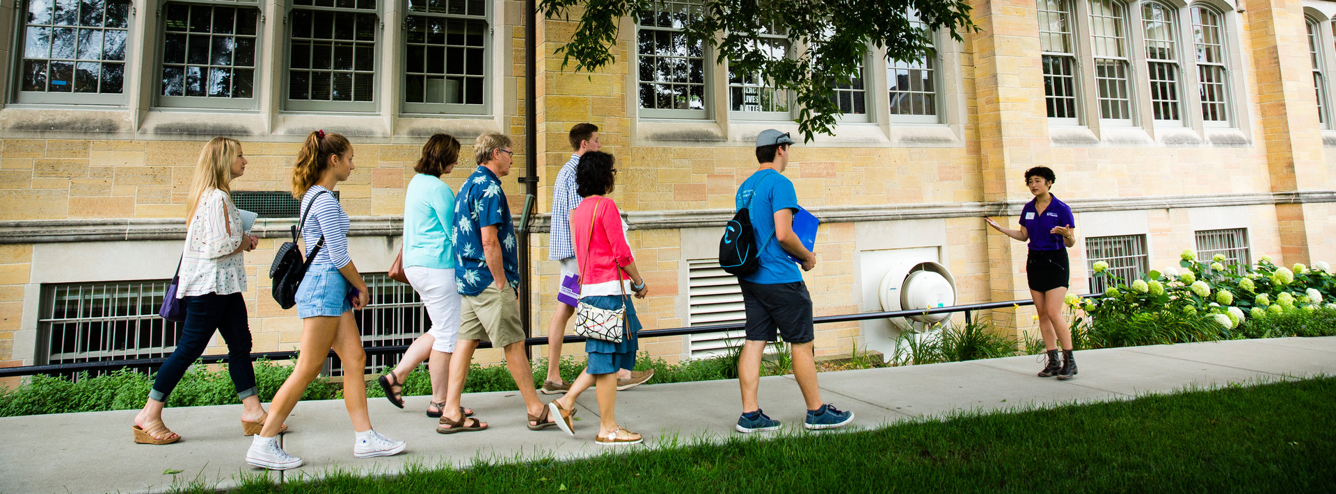 admissions counselor walking a tour group past john roach center