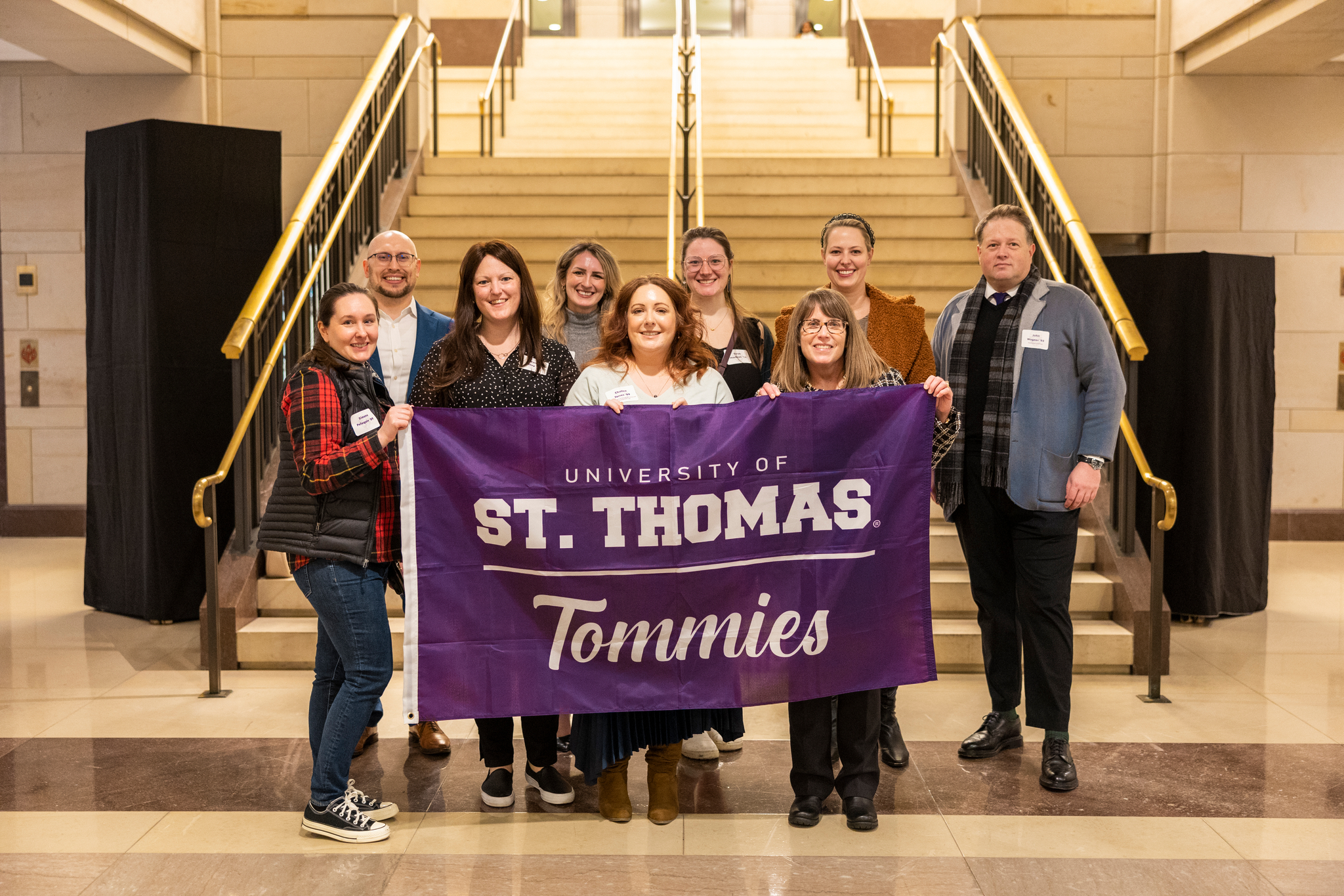 Alumni gathered in Washington D.C. holding a purple Tommie flag inside the Capitol